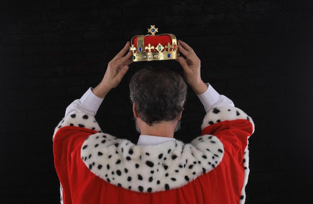 Premium Photo | A king wearing a crown is holding his head in the air.